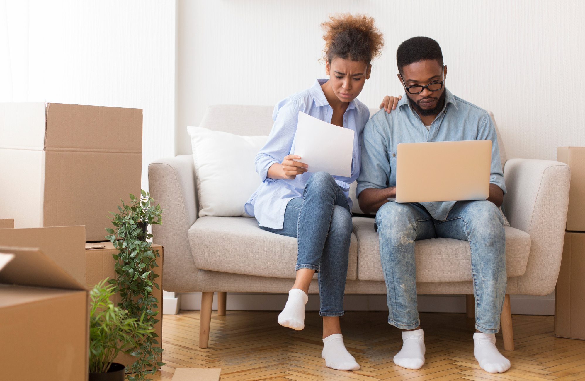 Serious Black Couple Reading Ownership Papers Sitting On Sofa Indoor